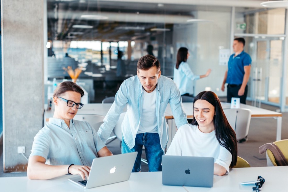 A team reviewing work together on laptops in a bright office
